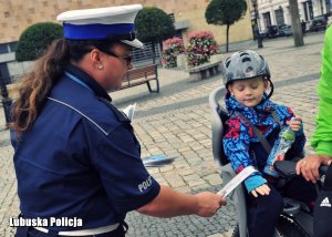 policjant zakłada na rękę dziecka element dblaskowy