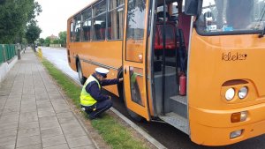 Policjant kontroluje stan techniczny autobusu szkolnego