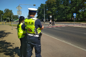 policjanci ruchu drogowego obserwują ruch pojazdów i pieszych na przejściu dla pieszych
