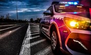 policyjny radiowóz z włączonymi światłami na drodze nieoświetlonej