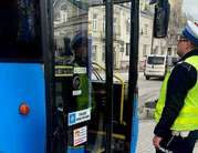 Policjant umundurowany stoi obok niebieskiego autobusu