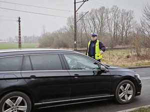 policjant w umundurowaniu stoi obok czarnego samochodu