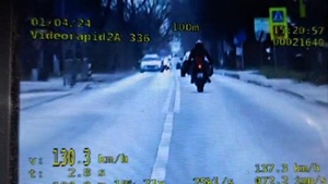 zdjęcie z policyjnego wideorejestratora, na którym widać jadącego motocyklistę i żółte napisy z urzadzenia