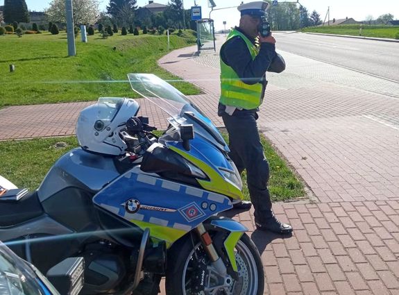 policjant stoi obok oznakowanego motocykla