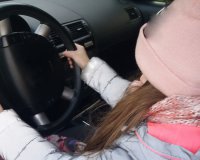 dziewczynka za kierownicąż samochodu