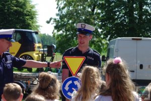 policjanci ruchu drogowego wyjaśniają dzieciom znaczenie znaków drogowych