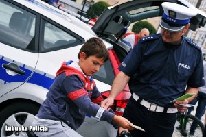 policjant zakłada na rękę dziecka element dblaskowy