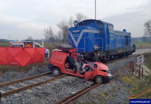 samochód w kolorze czerwony na torach kolejowych potrącony przez elektrowóz