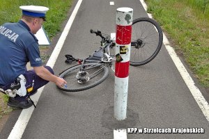 Policjant wykonuje opis roweru leżącego na drodze