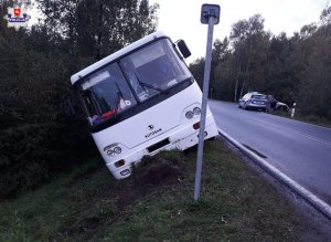 zdjęcie przestawia biały autobus, przechylony na jedna stronę, który znajduje się na poboczu
