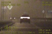 zdjęcie jest stopklatą z filmu zrobionego przez policyjny wideorejestrator, przedstawia samochód osobowy w ciemnym kolorze, ujecie zrobione jest z tylu pojazdu