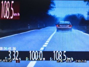 Zdjęcie jest stop-klatka z policyjnego wideorejestratora. Przedstawia tył pojazdu nieznanej marki. Na zdjęciu widać odczyt prędkości z jaka pojazd się porusza tj. 108 km/h
