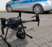 Zdjęcie prezentuje drona w kolorze czarnym stojącego na na ziemi