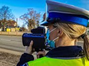Zdjęcie przedstawia zbliżenie umundurowanej policjantki, która dokonuje pomiaru prędkości wideorejestratorem.