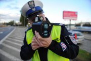 Policjant obsługujący wideorejestrator stoi przy drodze