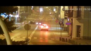 zdjęcie zrobione zostało późnym wieczorem, widać na nim oświetloną ulice oraz trzy pojazdy