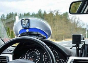 wnętrze policyjnego samochodu, widać kierownice i czapkę policyjna na desce rozdzielczej