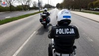 dwóch policjantów umundurowanych na motocyklach porusza się drogą, maja ciemne kurtki motocyklowe, na których widnieje napis Policja