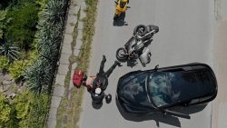 na jezdni leży motocykl, obok motocyklista, którego potracił samochód w kolorze czarnym