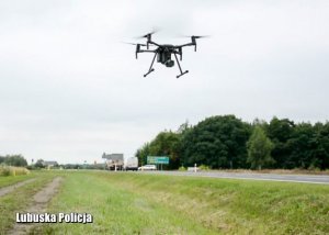 dron na tle nieba, w pobliżu przebiega ruchliwa droga