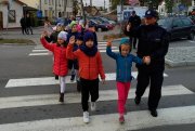 policjant przeprowadza przez przejście dla pieszych grupę dzieci