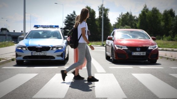 Dwie dziewczynki przechodzą przez przejście dla pieszych. Zdjęcie jest stop-klatka z filmu zamieszczonego pod tekstem.