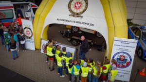 grupa dzieci w odblaskowych kamizelkach zebrana przy stoisku Automobilklubu Polski
