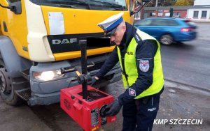 policjant ruchu drogowego sprawdza ustawienie świateł w ciężarowce przy pomocy specjalistycznego urządzenia