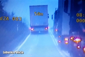 Obraz przedstawia samochód ciężarowy, który wyprzedza inne pojazdy ciężarowe