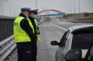dwóch policjantowi ruchu drogowego stoi obok samochodu w kolorze szarym