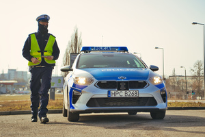 umundurowany policjant ruchu drogowego stojący w pobliżu oznakowanego radiowozu