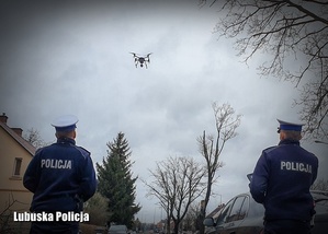 dwóch policjantów obserwuje znajdującego latającego drona
