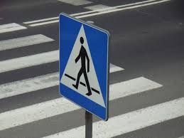 przejście dla pieszych z widocznym znakiem drogowym informacyjnym, na na niebieskim tle znaku biała sylwetka pieszego i białe pasy