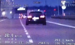 zdjęcie z policyjnego wideorejestratora jest nieostre, widać ciemny samochód oraz wyświetloną przez uprzedzenie prędkość 194,9 km/h