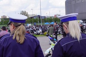 dwie policjantki ruchu drogowego stojące tyłem, w perspektywie widać zaparkowane motocykle uczestników sezonu motocyklowego