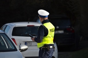 policjant stojący na tle białego samochodu