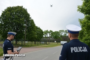 Na zdjęciu widać dwóch policjantów ruchu drogowego obsługujących drona.