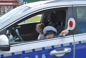 Na zdjęciu widać radiowóz policyjny i dwoje dzieci, które siedzą w radiowozie.