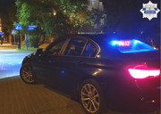 radiowóz nieoznakowany zaparkowany na nieoświetlonej ulicy z włączonym napisem Policja