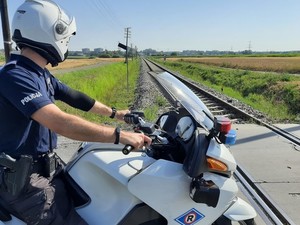 policjant na motocyklu obserwuje przejazd kolejowy