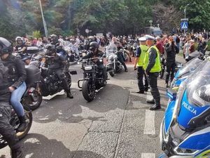 Zgromadzenie motocyklistów, wśród nich stoją umundurowani policjanci
