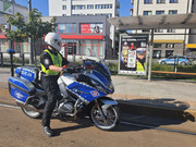 Policjant ruchu drogowego stoi obok służbowego, oznakowanego motocykla