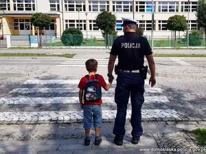 Policjant stoi z dzieckiem przy przejściu dla pieszych