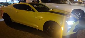 sceneria nocna, żółty samochód marki mustang stoi bok innych samochodów