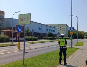 policjantka stoi przed budynkiem szkoły