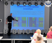 policjant pokazuje dzieciom slajd do nauki przepisów ruchu drogowego