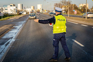 policjant ruchu drogowego zatrzymuje samochód osobowy do kontroli