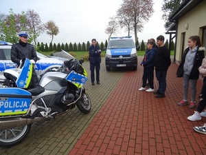 policyjne radiowozy i motocykl stoją przed szkoła, obok policjanci i uczniowie