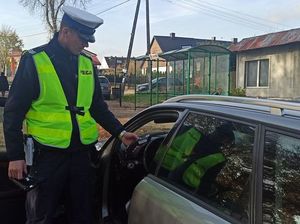umundurowany policjant stoi obok samochodu osobowego