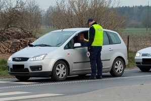 policjant stoi obok szarego samochodu
